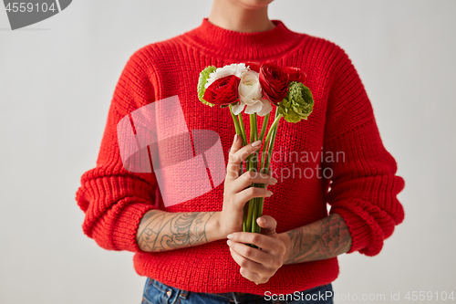 Image of A beautiful bouquet of flowers of a Ranunculus holding a girl around a gray background.