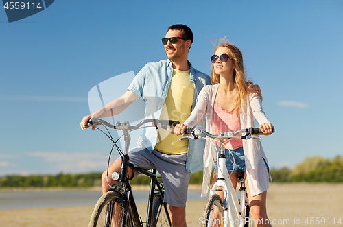 Image of happy young couple riding bicycles at seaside