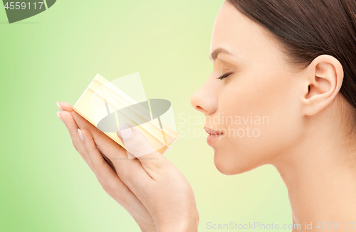 Image of beautiful woman smelling moisturizing cream aroma