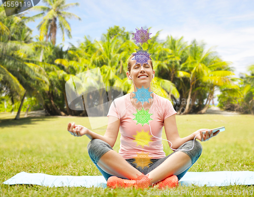 Image of woman meditating in summer park with seven chakras