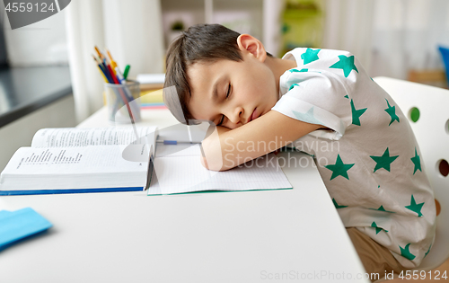 Image of tired student boy sleeping on table at home