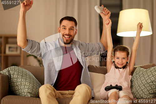 Image of father and daughter playing video game at home