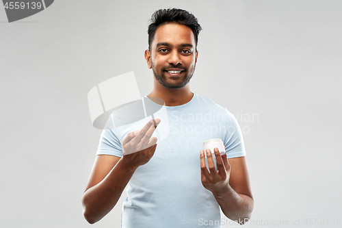 Image of happy indian man applying cream to face