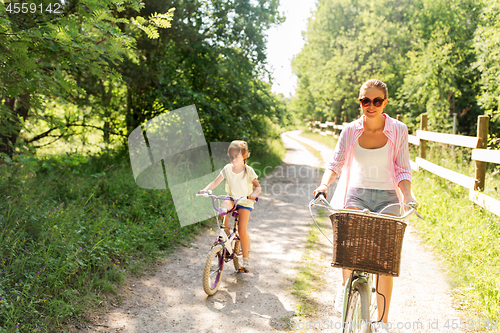 Image of mother and daughter riding bikes in summer park