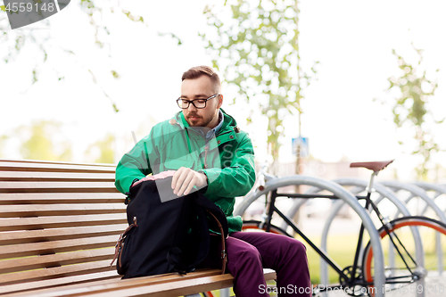 Image of man or hipster with backpack on street bench