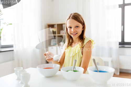 Image of girl coloring easter eggs by liquid dye at home