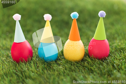 Image of easter eggs in party hats on artificial grass