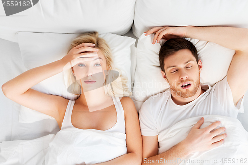 Image of unhappy woman in bed with snoring sleeping man