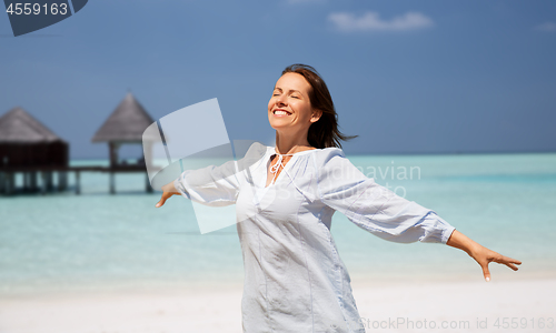 Image of happy woman over beach and bungalow on background