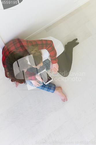 Image of Young Couple using digital tablet on the floor