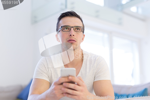 Image of young man using a mobile phone  at home