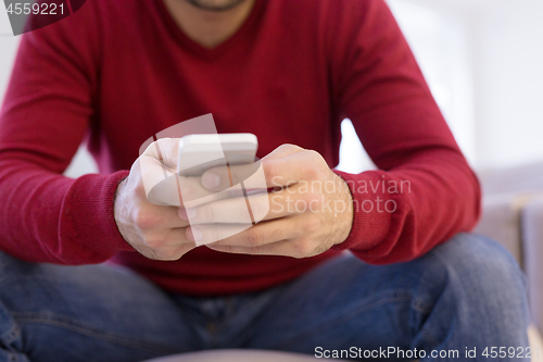 Image of young man using a mobile phone  at home