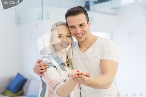 Image of couple showing small red house in hands