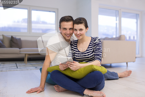 Image of Young Couple using digital tablet on the floor