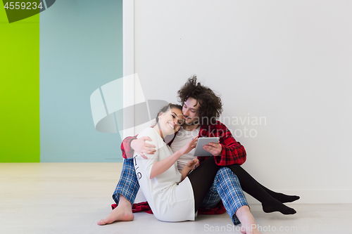 Image of Young Couple using digital tablet on the floor