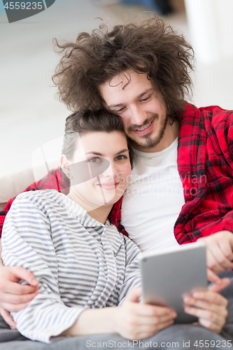 Image of couple relaxing at  home with tablet computers