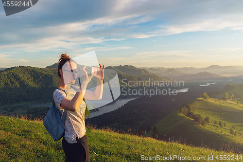 Image of Woman taking photo in mountain