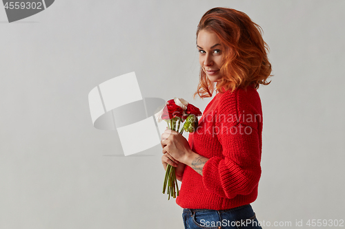 Image of Portrait of a beautiful woman with a bouquet of flowers is holding in her hands on a gray.