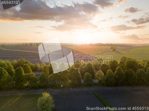 Image of Aerial view from the drone, a bird\'s eye view of abstract geometric forms of abandoned runway, forests and agricultural fields in the summer evening at sunset.