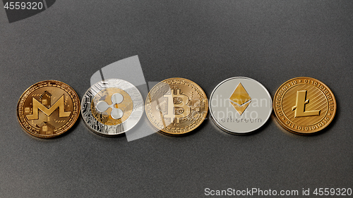 Image of Five different coins of crypto-currencies presented in a row on a dark background. Virtual money concept. Top view