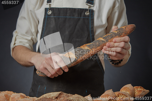 Image of Men\'s hands hold a baguette