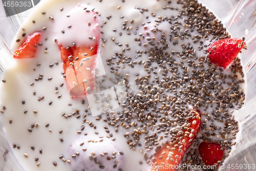 Image of healthy fruits smoothies with shia seeds and strawberries in blender, close up. Flat lay