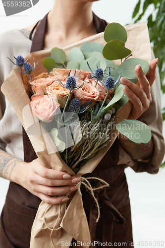 Image of Fresh amazing flowers bouquet in a woman\'s hands with tattoo on a white background. Greeting card.