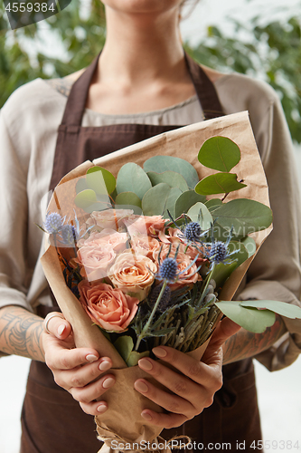Image of Young girl hold fresh natural floral bouquet with roses, eryngium and green leaves. Concept of Mother\'s Day.