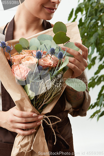 Image of Close-up of greeting flowers bouquet of fresh natural roses living coral color in a florist girl\'s hands on a white background with green leaf.