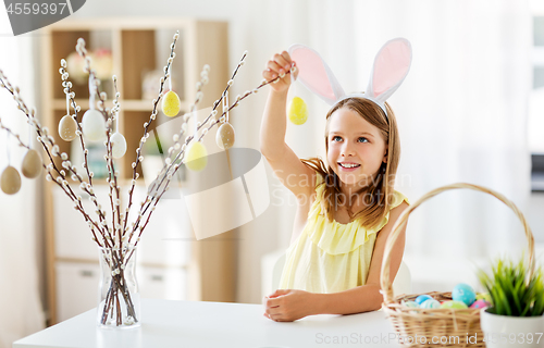 Image of girl decorating willow by easter eggs at home