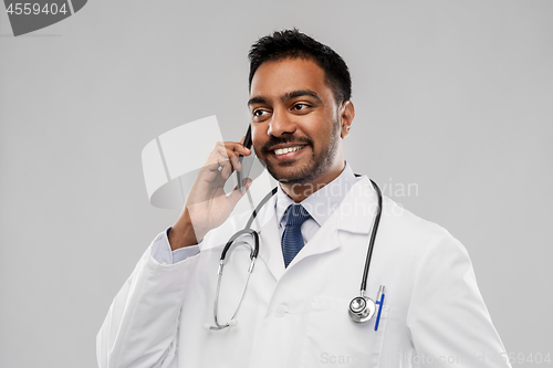 Image of smiling indian male doctor calling on smartphone