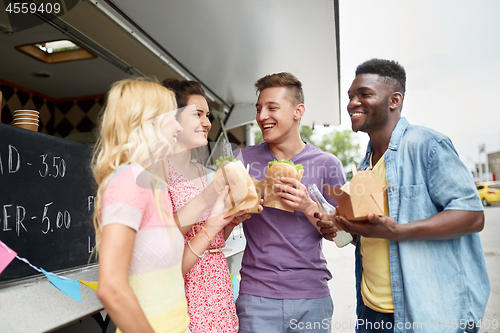 Image of happy friends with drinks eating at food truck