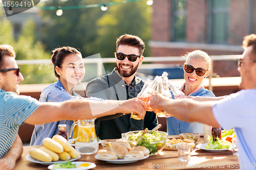 Image of happy friends toasting drinks at rooftop party