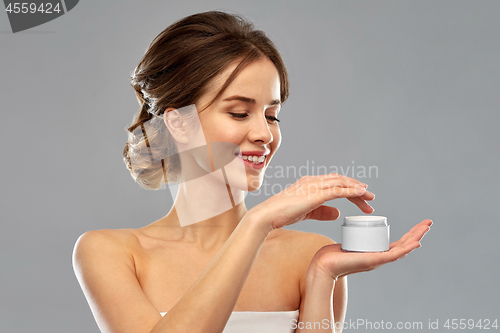 Image of happy young woman holding jar of cream