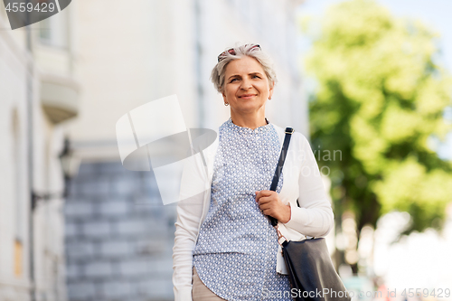 Image of happy senior woman on city street in summer