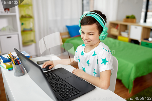 Image of boy in headphones playing video game on laptop