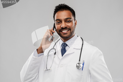 Image of smiling indian male doctor calling on smartphone