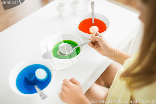 Image of girl coloring easter eggs by liquid dye at home