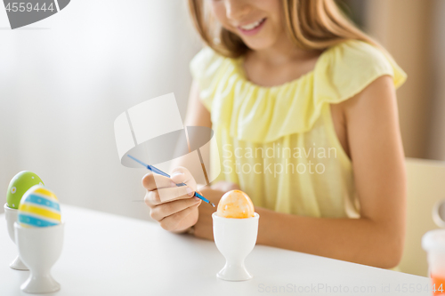 Image of close up of girl coloring easter egg by paintbrush