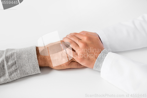 Image of close up of doctor holding senior patient hand