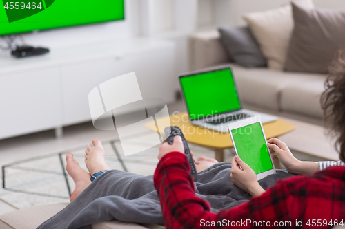 Image of couple relaxing at  home with tablet computers