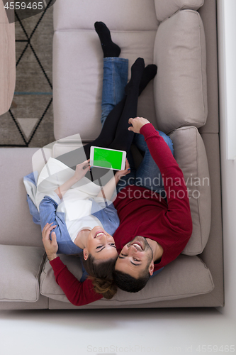 Image of couple relaxing at  home with tablet computers