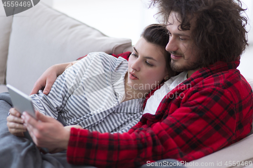 Image of couple relaxing at  home with tablet computers