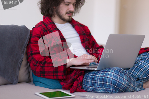 Image of man freelancer in bathrobe working from home