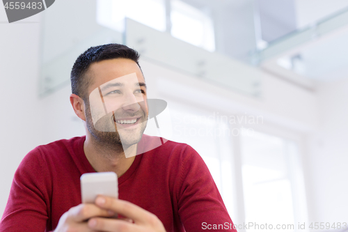 Image of young man using a mobile phone  at home