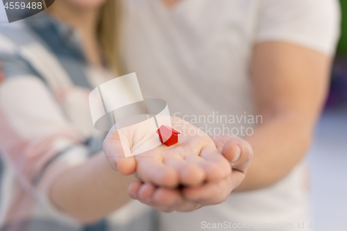 Image of couple showing small red house in hands