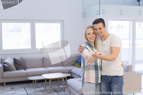 Image of couple showing small red house in hands