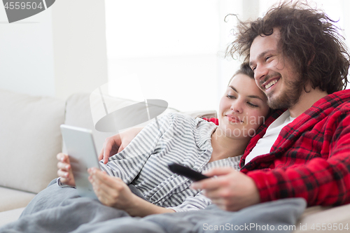 Image of couple relaxing at  home with tablet computers