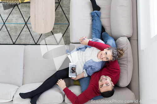 Image of couple relaxing at  home with tablet computers