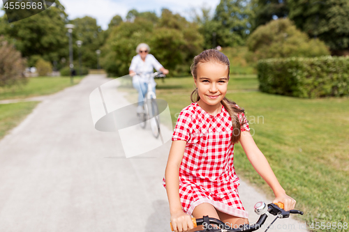 Image of grandmother and granddaughter cycling at park